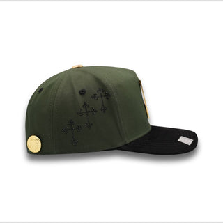 Olive green snapback cap with black rhinestone crosses and gold coin detail on side panel.