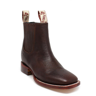 A brown, square-toed ankle boot with a leather shaft and a low heel, featuring the El Canelo brand name on the pull tab.