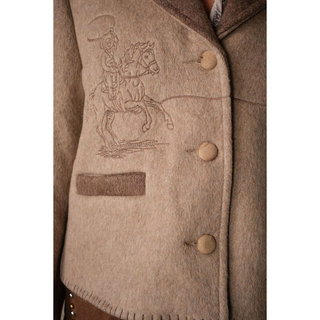 Close-up of cowboy and rope embroidery on a women’s two-tone western jacket with brown lapels and blanket stitching.