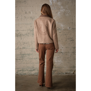 Back of women’s taupe western jacket featuring an embroidered horseshoe and “Wild Horses Run Free” lettering.
