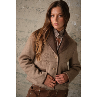 Close-up of cowboy and rope embroidery on a women’s two-tone western jacket with brown lapels and blanket stitching.
