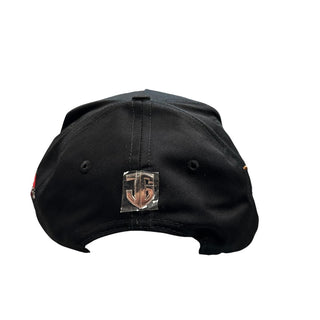 Back view of black JG Tomateros snapback hat with metallic rear logo emblem