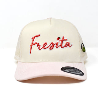 Front view of cream and pink Fresita snapback cap with embroidered red script and small strawberry detail on the letter i