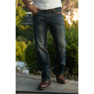 Full-body outdoor shot of model wearing Platini Holt Dark Stone Slim Boot Cut Jeans with boots.