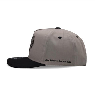 Side view of gray snapback showing embroidered text “Hoy Platique Con Mi Gallo”