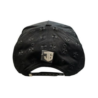Back view of black JG clover snapback hat with adjustable snapback closure and metallic logo emblem