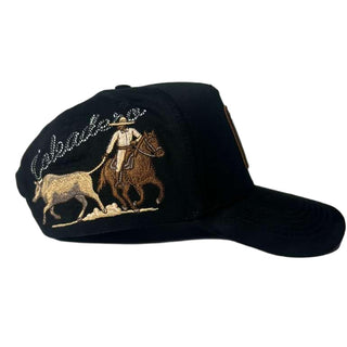 Black cap with embroidered design of a person on horseback and text on a light gray background