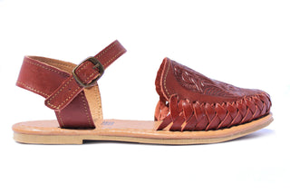 Side view of chestnut colored leather closed toe sandal with an ankle buckle and a floral imprint on the face