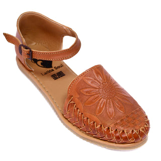 Honey colored leather closed toe sandal with an ankle buckle and a sunflower imprint on the face